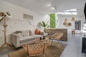 A modern living space with a sofa, chairs, a coffee table, a plant, and a white brick wall. - Private House Provenza Big Jacuzzi (Medellín)