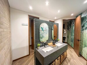 Ein modernes Badezimmer mit einer Granittheke, zwei Waschbecken und einem großen Spiegel.