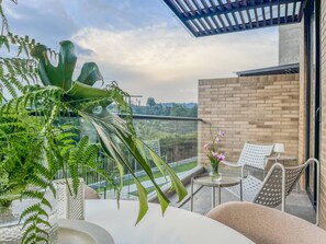 Ein Balkon mit Tisch, Stühlen und Blumentöpfen.