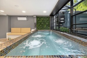 A spa area with a hot tub, a beige sofa, and a green wall. - Clean Design Prime Area Effortless Stay Poblado (Medellín)