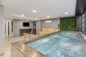 A modern indoor swimming pool area with a seating area and a bar. - Clean Design Prime Area Effortless Stay Poblado (Medellín)