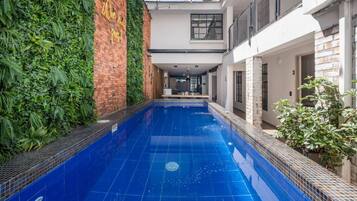 Una piscina con revestimiento azul de baldosas, rodeada por un muro de ladrillo y un jardín vertical.