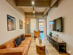 Ein modernes Wohnzimmer mit einer Couch, einem Couchtisch und einem Fernseher.