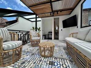 A rooftop terrace with wicker furniture, a patterned floor, and a TV mounted on the wall. - Luxe Retreat Private Pool Rooftop Provenza (Medellín)
