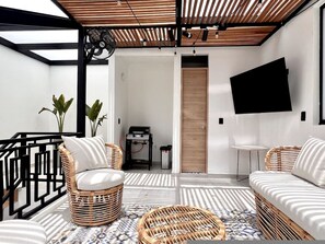 A modern living room with a flat-screen TV, wicker furniture, and a patterned floor. - Luxe Retreat Private Pool Rooftop Provenza (Medellín)