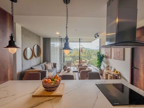 A modern kitchen with a marble countertop, a fruit basket, and a dining area with a view. - Modern Apartment El Retiro Forest View (Retiro)