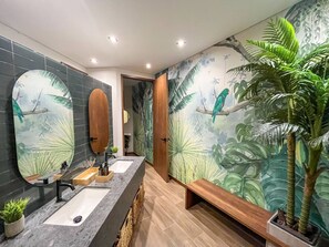 A bathroom with a long vanity, a large mirror, and a wall mural of a tropical scene. - Modern Apartment El Retiro Forest View (Retiro)