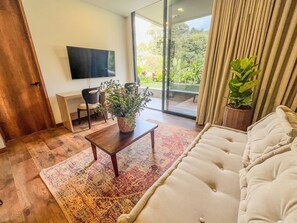 Ein modernes Wohnzimmer mit Sofa, Couchtisch, Fernseher und einem Balkon mit Pflanzen.