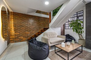 A modern living room with a brick wall, a staircase, a sofa, a bean bag, and a coffee table. - Nowa Huge PH Indoor Pool Jacuzzi Lleras Park (Medellín)