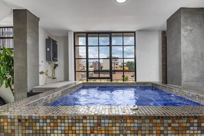 A hot tub with a tiled floor and a view of buildings through large windows. - Nowa Huge PH Indoor Pool Jacuzzi Lleras Park (Medellín)