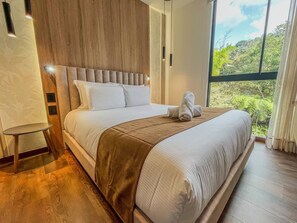 A modern hotel room with a large bed, a view of greenery, and a wooden floor. - Modern Loft El Retiro Balcony Quiet (Retiro)