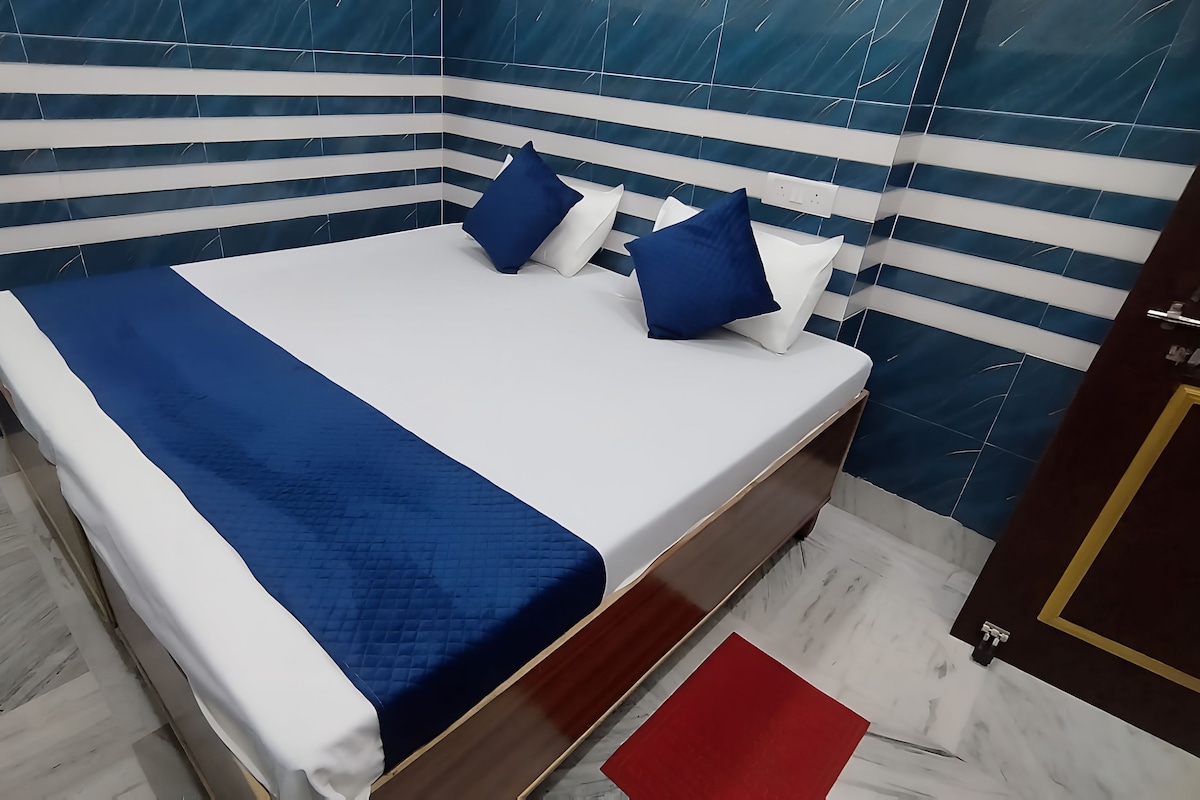 A bed with a blue and white bedspread, two blue pillows, and a red rug.