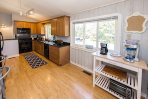 A kitchen with wooden cabinets, a black stove, a sink, and a window with a view of the outdoors. - Carefree - 5 BR north end home with Lake Tecumseh access (Virginia Beach)