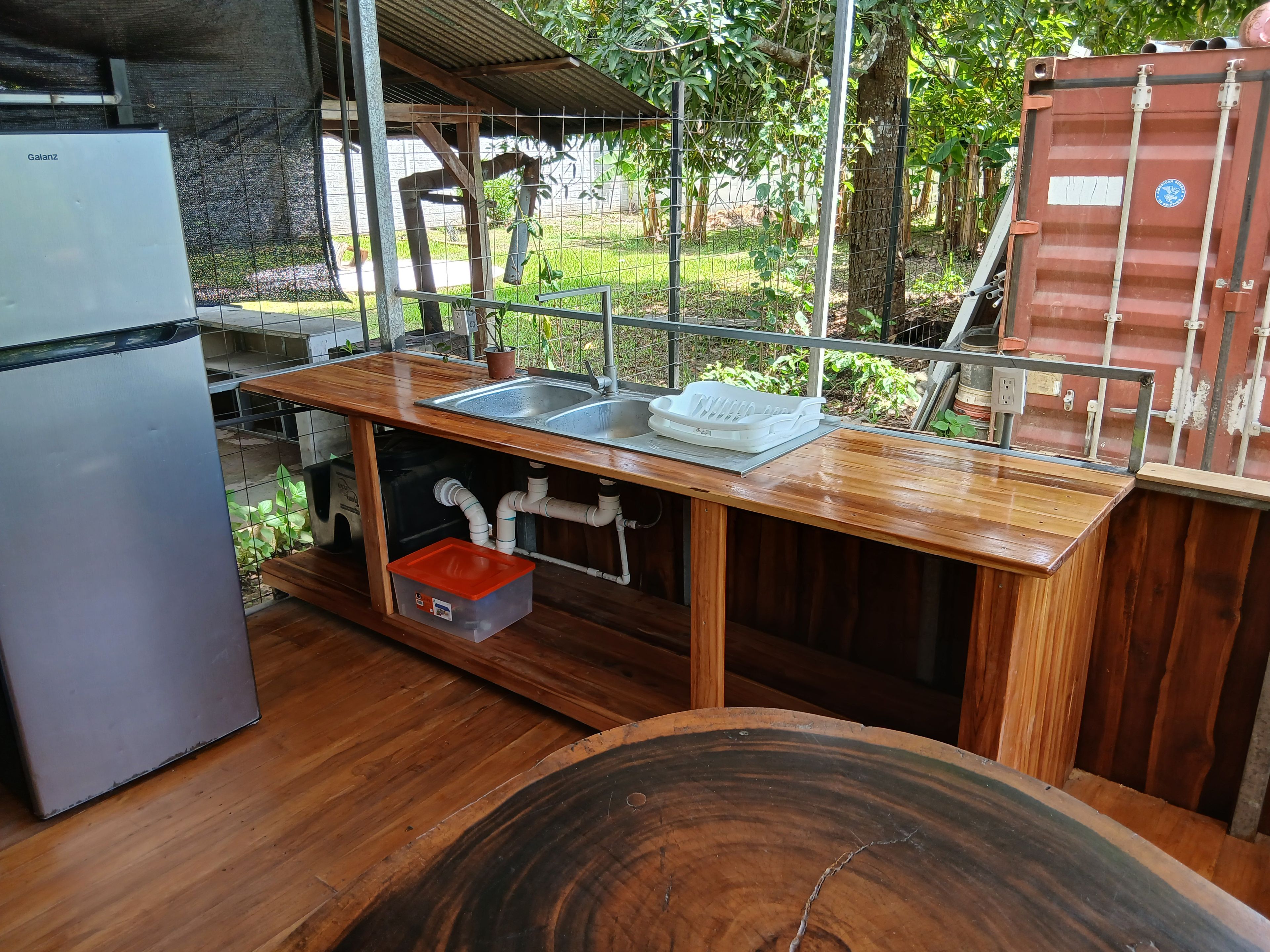 Cocina compacta con pileta integrada, refrigerador y encimera de madera.