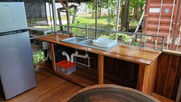 Cocina compacta con pileta integrada, refrigerador y encimera de madera.