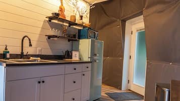 Een kleine keuken met een inbouwmagnetron, een koffieapparaat en een gootsteen.