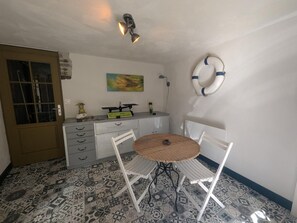 A room with a patterned floor, a round table with chairs, a desk with drawers, a door, and a wall-mounted life preserver. - La Passerelle - CIREY SUR BLAISE (CIREY SUR BLAISE)
