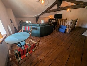 A cozy room with a wooden floor, a green sofa, a small table with chairs, and a television. - La Passerelle - CIREY SUR BLAISE (CIREY SUR BLAISE)