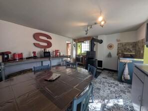 Una cucina con un tavolo da pranzo, sedie, un fornello e una grande lettera 'S' appesa al muro.