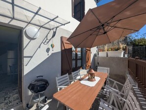 An outdoor patio with a wooden table and chairs, a barbecue grill, and a large umbrella providing shade. - La Passerelle - CIREY SUR BLAISE (CIREY SUR BLAISE)