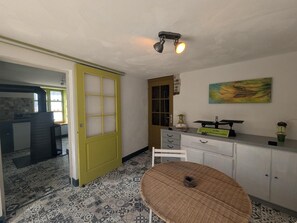 A room with a patterned floor, a yellow door, a white cabinet with drawers, a round table, and a painting on the wall. - La Passerelle - CIREY SUR BLAISE (CIREY SUR BLAISE)