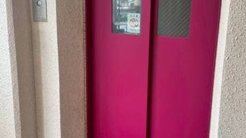 A red door with a security keypad and a no-touch warning sign.