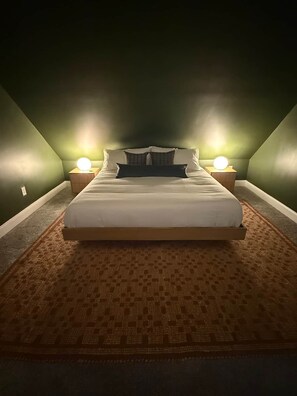 Een slaapkamer met een bed, twee bedlampen en een kamerkleed met dessin.