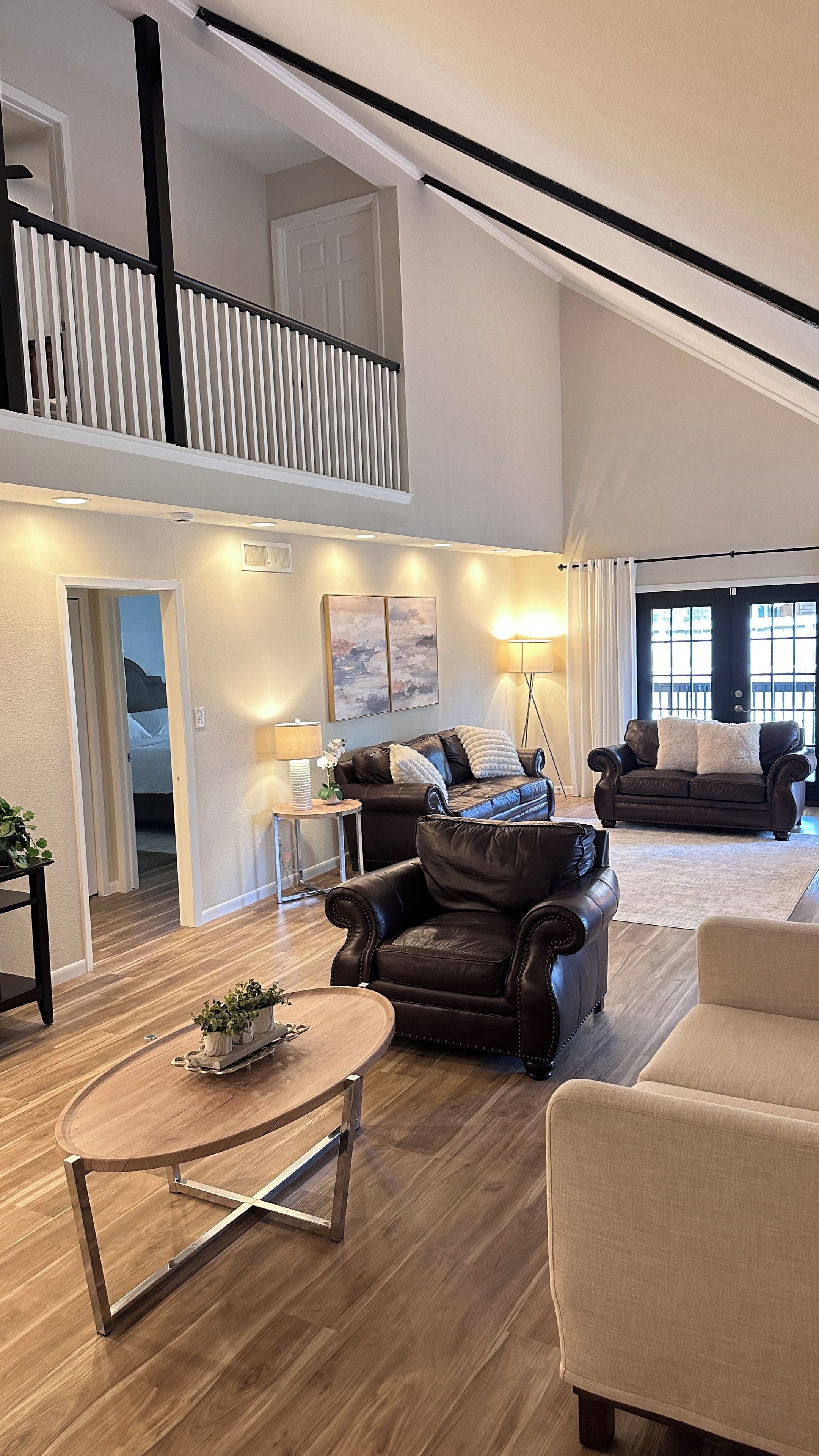 Un vaste espace de vie doté d’un haut plafond, d’une cheminée, d’un canapé, d’une table basse et offrant une vue sur l’extérieur.