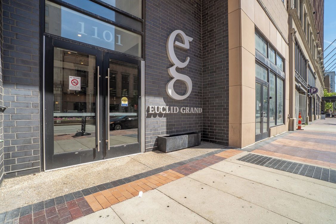A building with a large glass entrance, a prominent 'Euclid Grand' sign, and a parking sign.