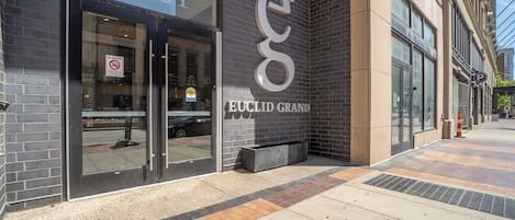 A building with a large glass entrance, a prominent 'Euclid Grand' sign, and a parking sign.