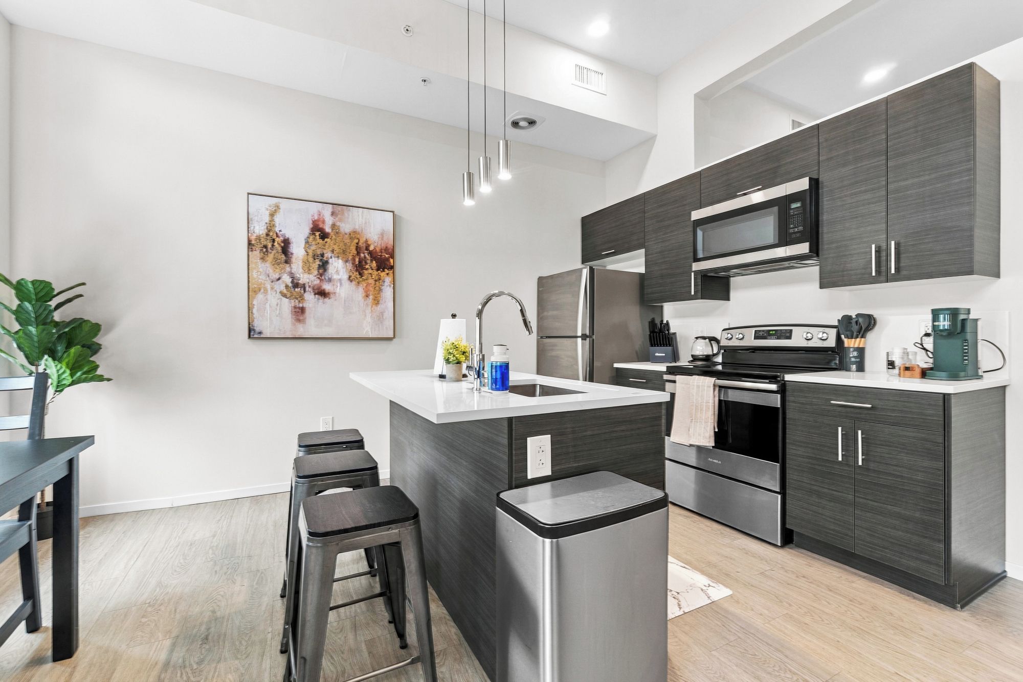 A modern kitchen with a central island, stainless steel appliances, and dark cabinetry.