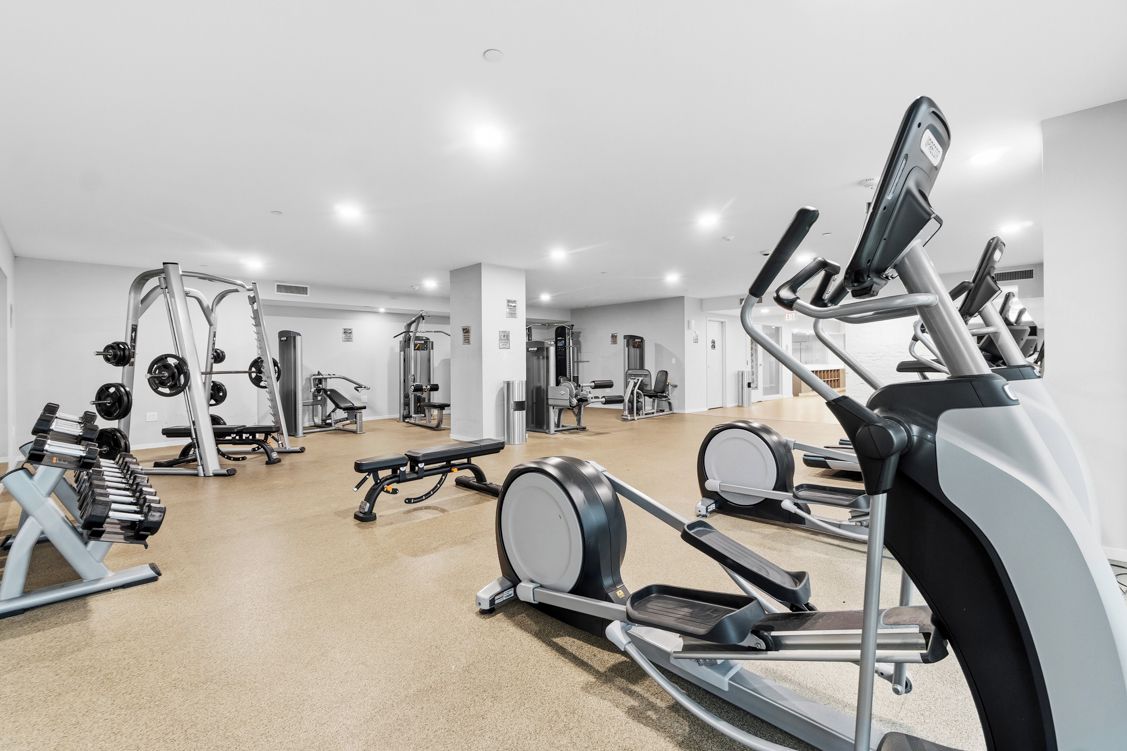 Une salle de sport équipée de divers appareils d’entraînement, notamment des tapis de course, des appareils de musculation et des poids libres.