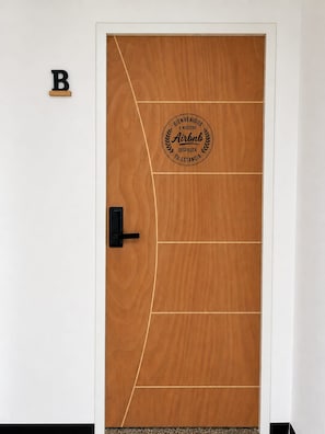 Eine Holztür mit einem runden Airbnb-Logo und einem schwarzen Griff.