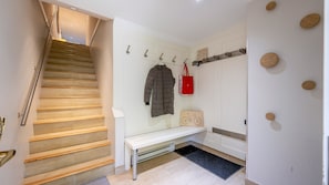 A staircase leading to a landing with a coat rack, a bench, and a wall-mounted coat storage. - New Listing | Beautifully Updated 3BR | Close to Village & Lost Lake | Managed By Aloha Whistler (Whistler)