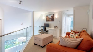 A modern apartment with a balcony, a desk with a computer, a sofa with patterned cushions, and a painting on the wall. - New Listing | Beautifully Updated 3BR | Close to Village & Lost Lake | Managed By Aloha Whistler (Whistler)