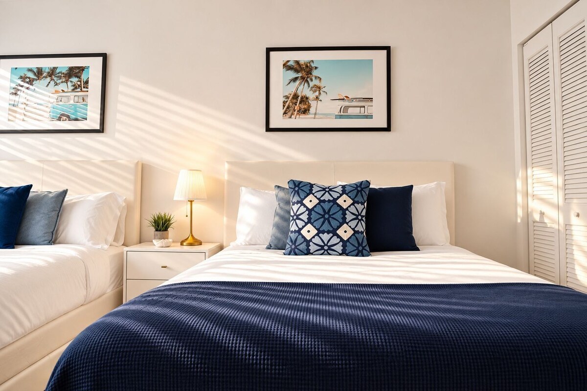 A hotel room with a bed, two bedside tables, a lamp, and two framed pictures on the wall.