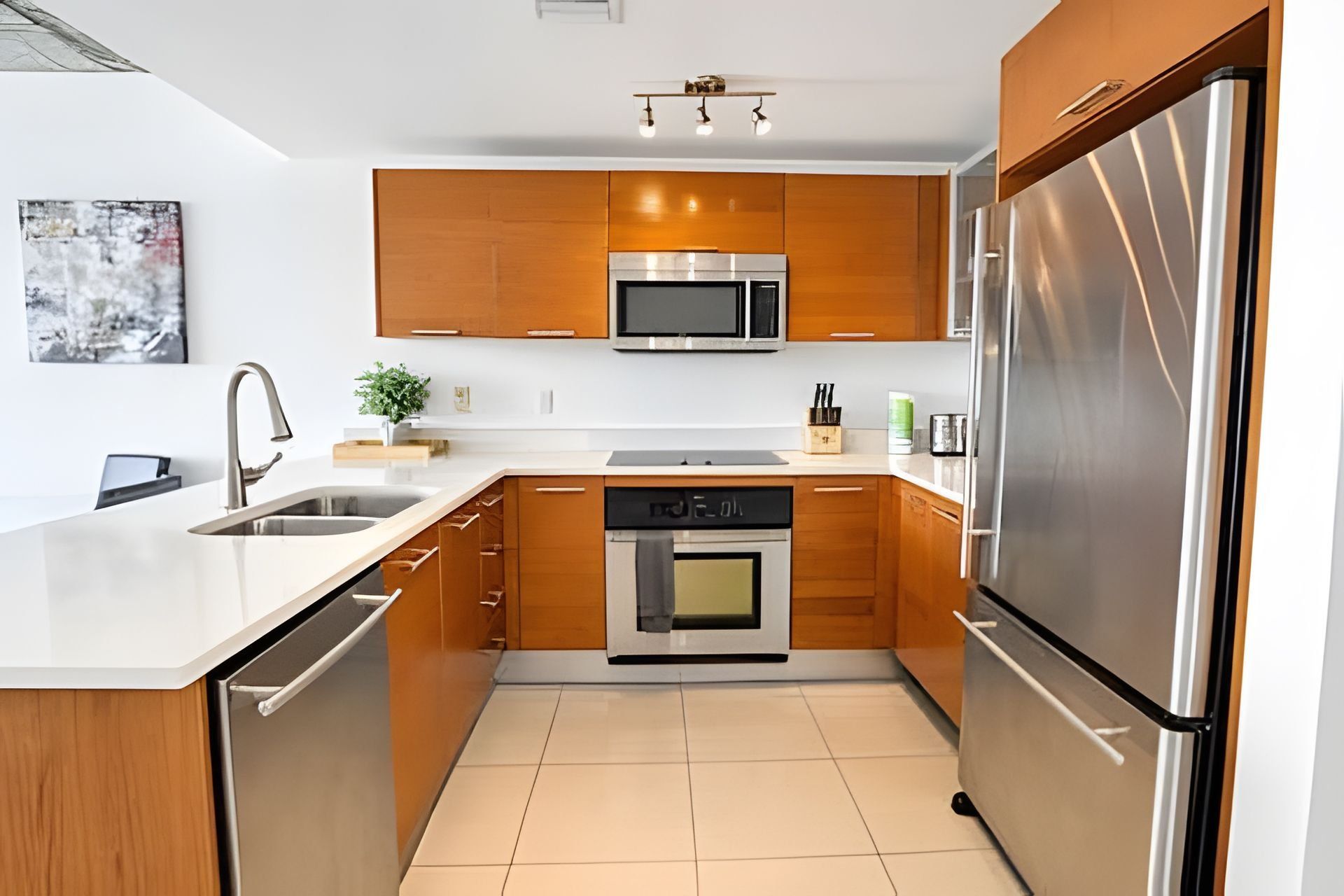 A modern kitchen with wooden cabinets, stainless steel appliances, and a white countertop.