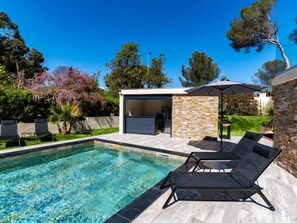 A modern outdoor pool area with clear water, lounge chairs, and a stone wall structure. - Villa for 18 people • 3 apartments • Swimming pool (Saint-Raphaël)
