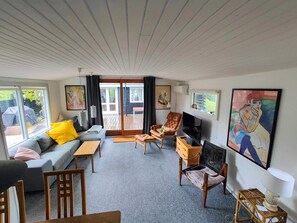 Ein Wohnzimmer mit einer Couch, Sesseln, einem Fernseher und Kunstwerken an den Wänden.