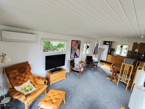 Ein gemütlicher Wohnraum mit einer Couch, einem Fernseher und einer Küchenzeile.