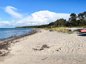 Een zandstrand met boten en een bebost gebied op de achtergrond.