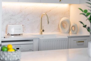 A modern kitchen with a white countertop, a gold faucet, and a built-in microwave. - Belle Escapes Aquarius' Panoramic Jewel 11th Floor (Cairns City)