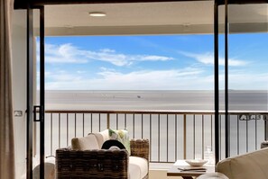 A balcony with a view of the sea, wicker furniture, and a small table with a glass. - Belle Escapes Aquarius' Panoramic Jewel 11th Floor (Cairns City)