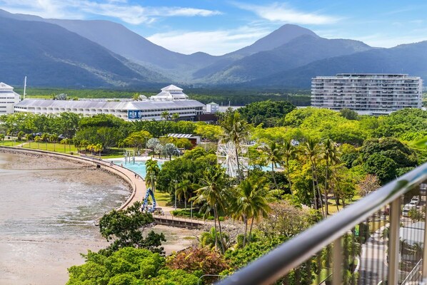 A resort with a pool, palm trees, and mountains in the background. - Belle Escapes Aquarius' Panoramic Jewel 11th Floor (Cairns City)