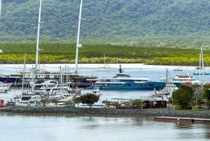 A marina with various boats docked, surrounded by a forested hillside. - Belle Escapes Aquarius' Panoramic Jewel 11th Floor (Cairns City)