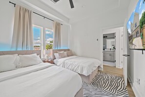Ein Schlafzimmer mit zwei Betten, einem zebra-gemusterten Teppich und Blick ins Freie.