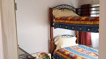 A room with a bunk bed, a small wooden desk, and a toy house.