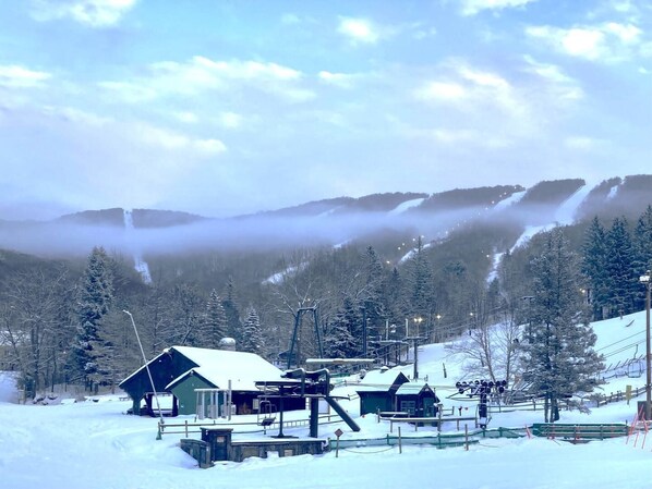 A snow-covered ski resort with buildings, a ski lift, and a mountain backdrop.