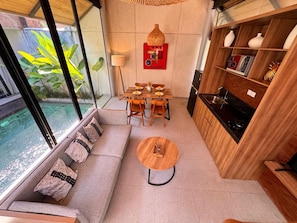 A compact living space with a sofa, dining table, and kitchenette. - Villa Jia by Kelle, Ubud (Gianyar)