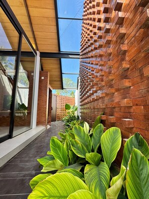 A modern building with a brick wall and large windows. - Villa Jia by Kelle, Ubud (Gianyar)